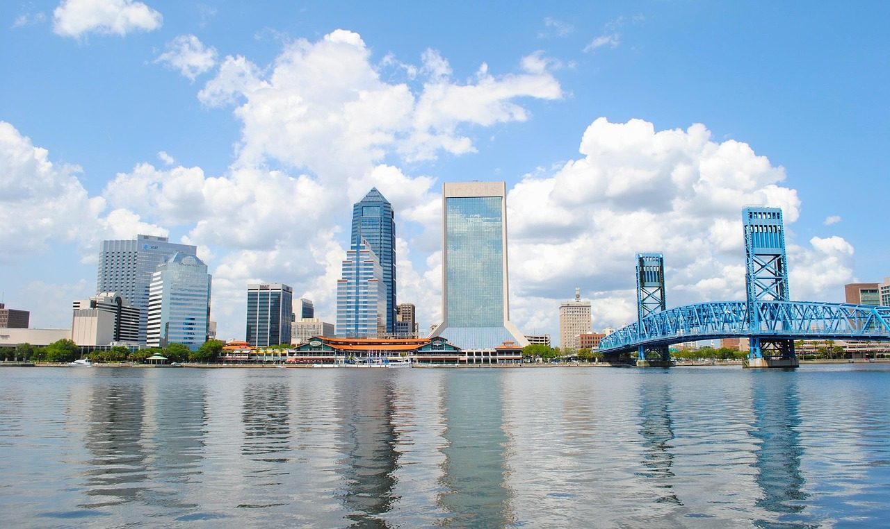 Jacksonville skyline and harbor reflected in bay water beneath clouds